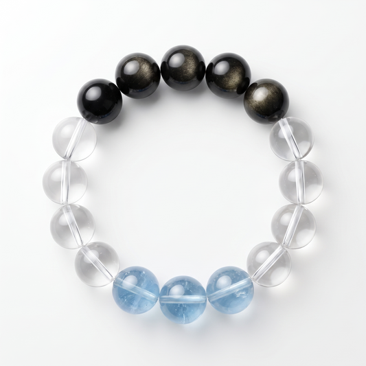 Krysora Gilded Tide — aquamarine, clear quartz and gold sheen obsidian beads, sea-blue and dark ink on white.