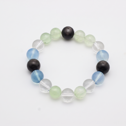 Confluence bracelet by Krysora - Silver Sheen Obsidian, Aquamarine and Prehnite with Clear Quartz accents, deep blue-black and living green cool palette, product photo on white background