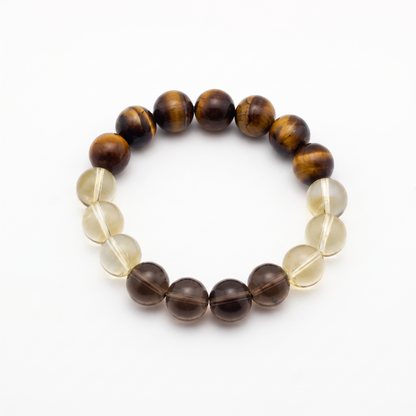 Krysora Bedrock — warm ochre and smoky quartz beads, clay-toned gold and gray on white.