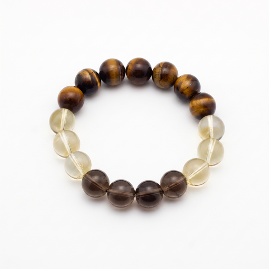 Krysora Bedrock — warm ochre and smoky quartz beads, clay-toned gold and gray on white.