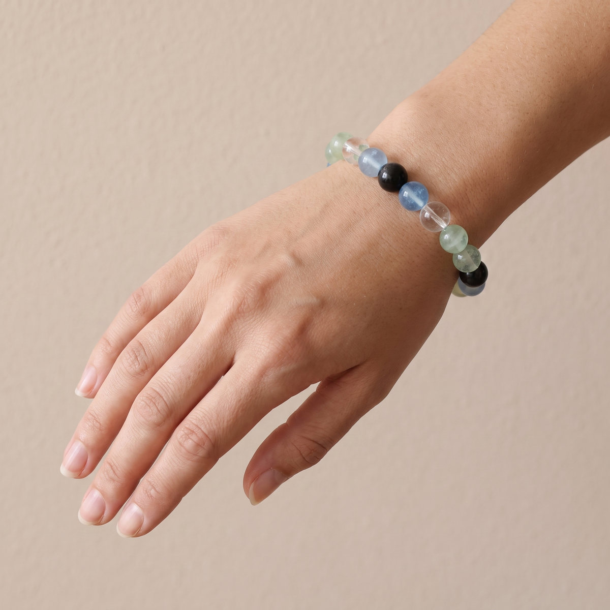 Confluence bracelet by Krysora worn on a woman's wrist - deep blue-black obsidian with blue-green aquamarine