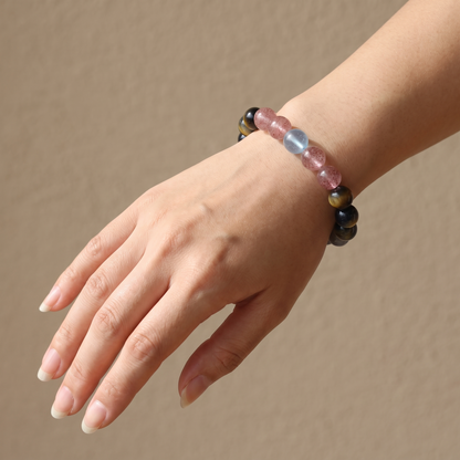 Tri-Sheen bracelet by Krysora worn on a woman's wrist - clear blue, warm ochre, and berry-red three-tone gemstones