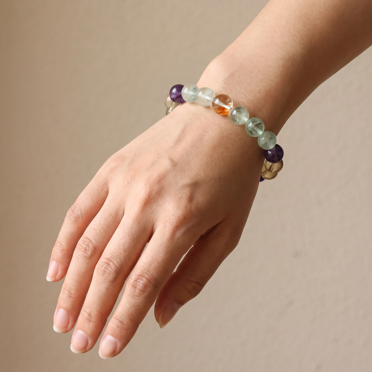Tri-Cultivate bracelet by Krysora worn on a woman's wrist - warm red, honey gold and soft green gemstones