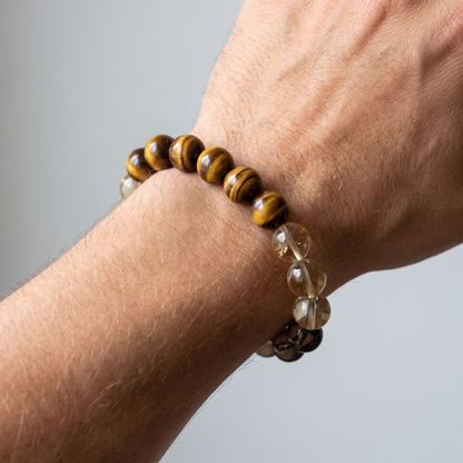 Bedrock on a man's wrist — tiger's eye gold and smoky gray in warm daylight.