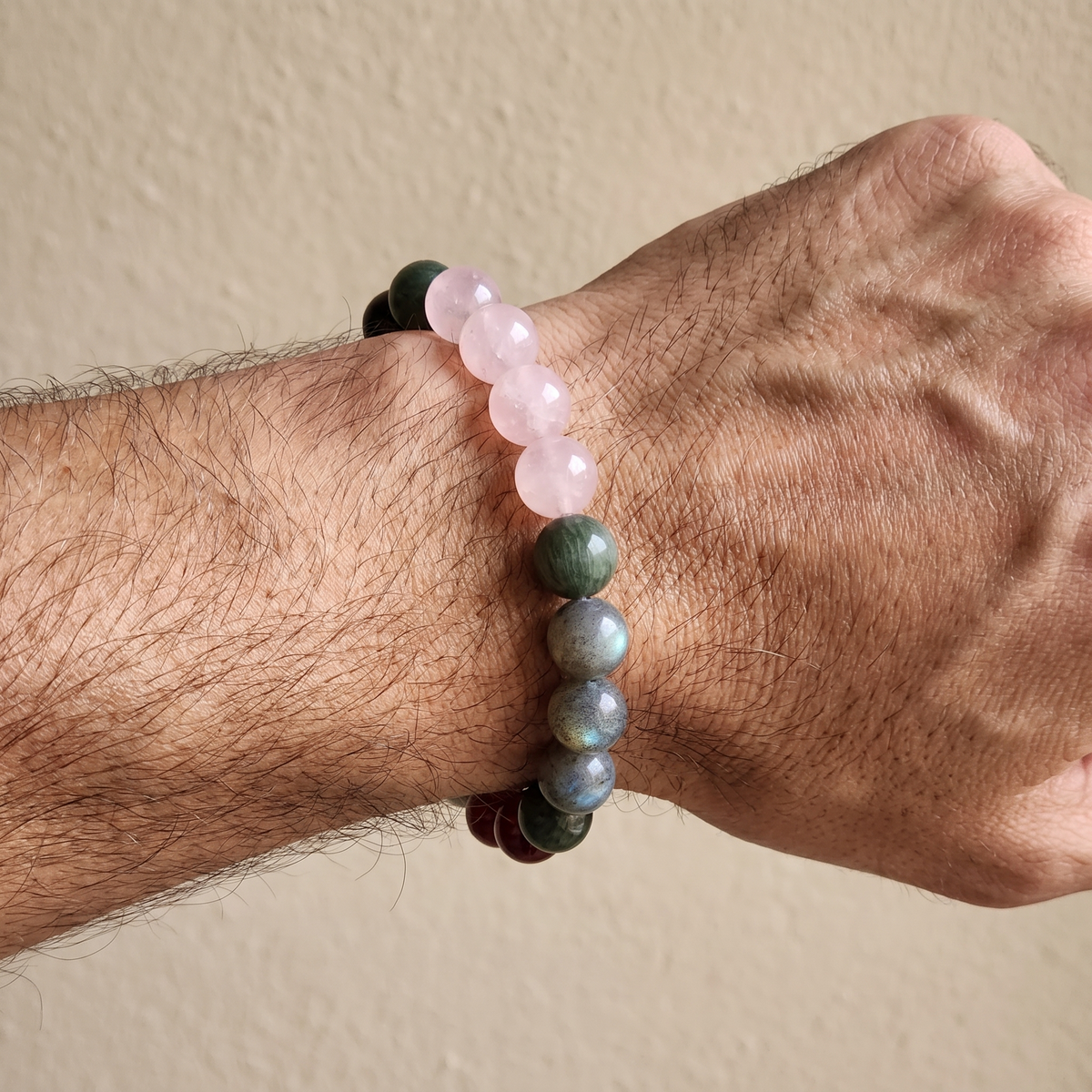 Aqua Ember bracelet by Krysora worn on a man's wrist - deep ink obsidian with rosy quartz and red garnet glow