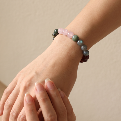Aqua Ember bracelet by Krysora worn on a woman's wrist - deep ink obsidian with rosy quartz and red garnet glow