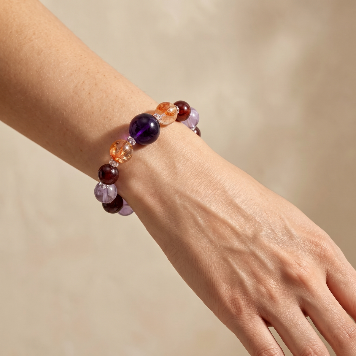 Southern Flame on a woman's wrist — glowing purple-red amethyst, garnet and hematoid quartz.