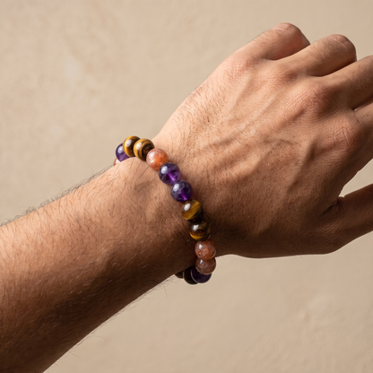 Solar Blaze on a man's wrist — amethyst, golden sunstone and tiger's eye, warm gold-purple tones.