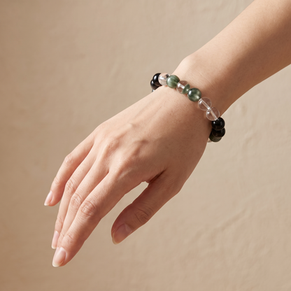 Golden Channel bracelet by Krysora worn on a woman's wrist - silvery black obsidian with fresh green rutilated and phantom quartz