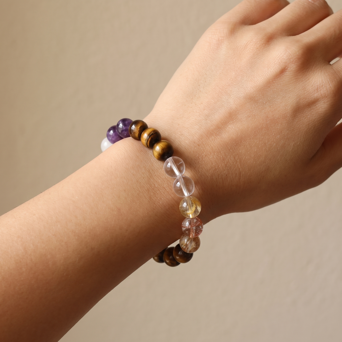 Ember Gold bracelet by Krysora worn on a woman's wrist - golden-brown tiger's eye with warm red hematoid glow