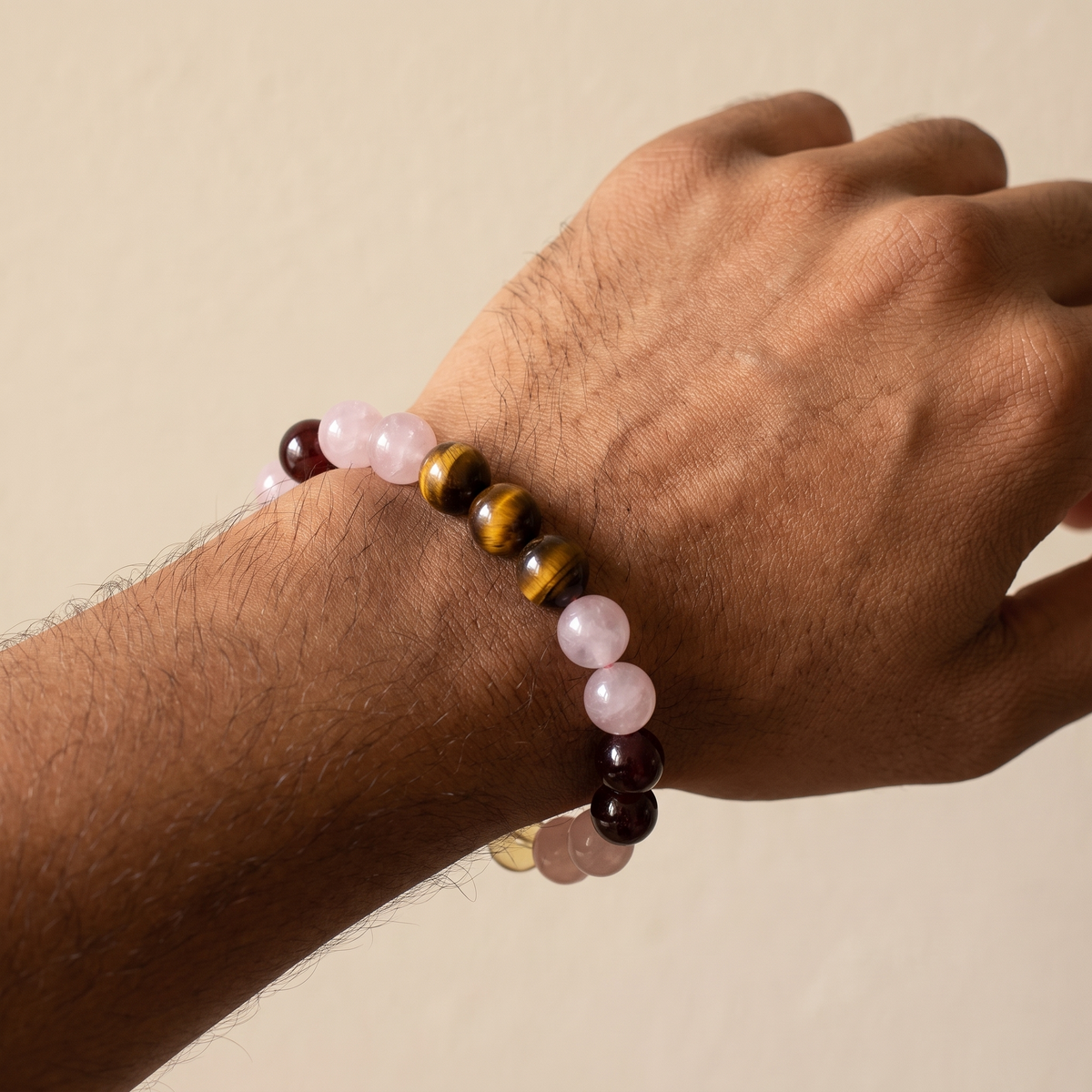 Ember Bloom bracelet by Krysora worn on a man's wrist - soft pink, golden-brown, warm red and bright yellow beads