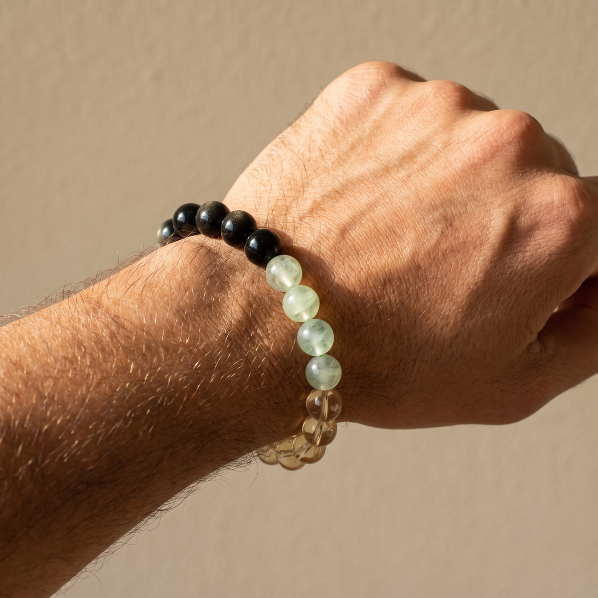 Tri-Flourish bracelet by Krysora worn on a man's wrist - dark obsidian, warm gold citrine, and misty green prehnite