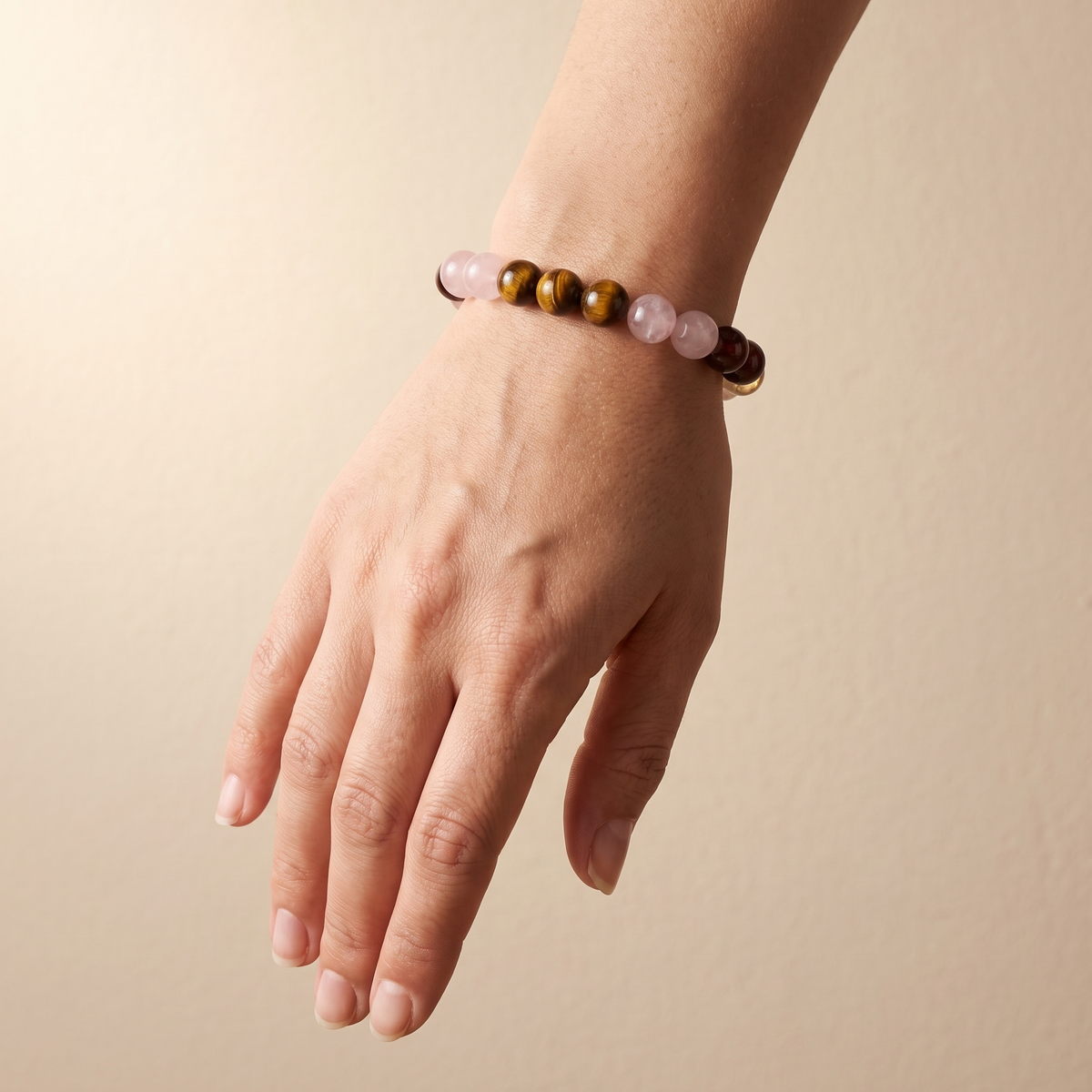 Ember Bloom bracelet by Krysora worn on a woman's wrist - soft pink, golden-brown, warm red and bright yellow beads