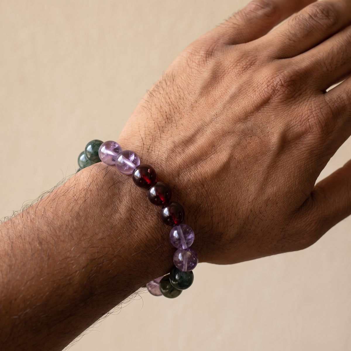 Verdant Spark bracelet by Krysora worn on a man's wrist - sprouting green, quiet violet and warm ember beads