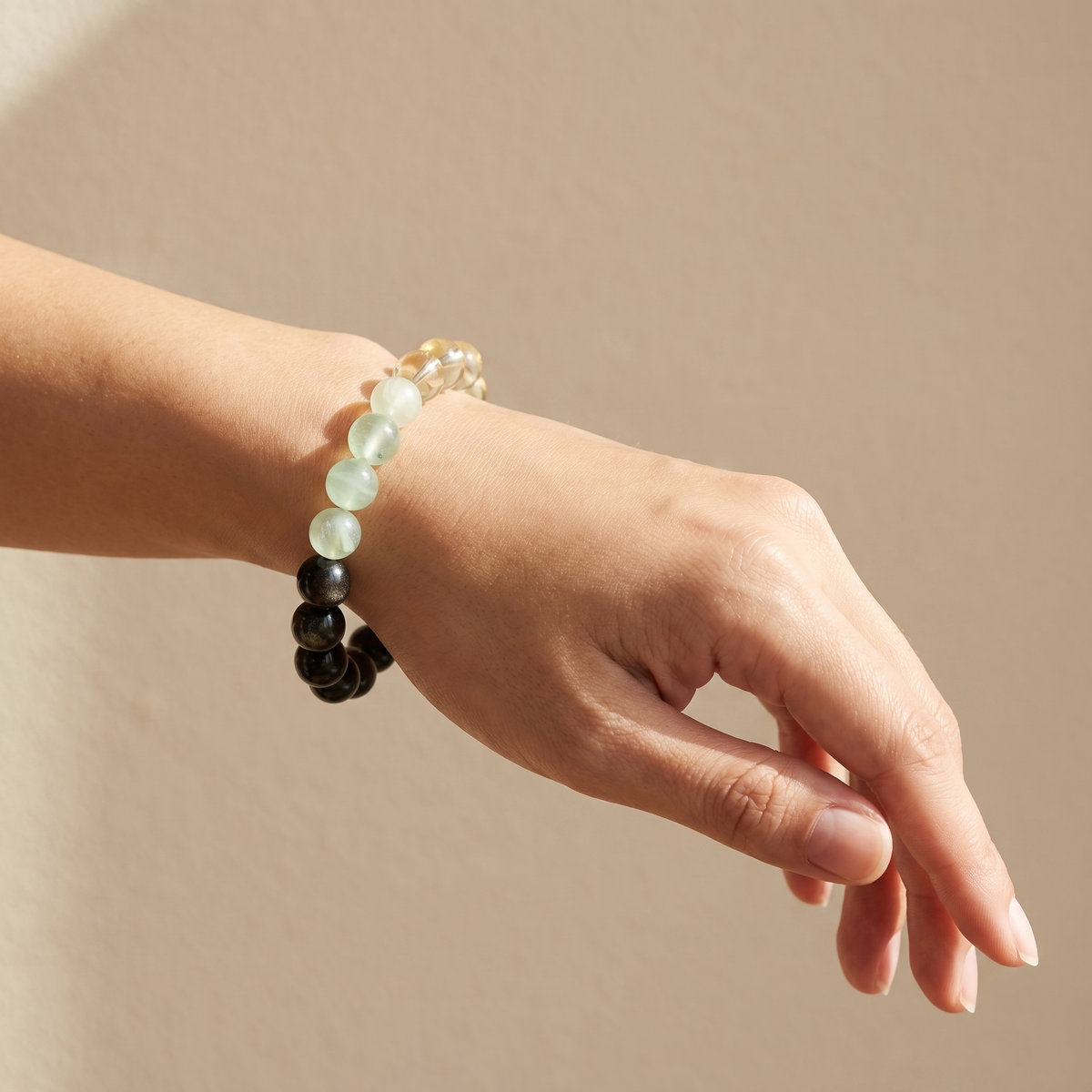 Tri-Flourish bracelet by Krysora worn on a woman's wrist - dark obsidian, warm gold citrine, and misty green prehnite