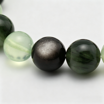 Close-up of the Aqua Verdance bracelet by Krysora - bead detail, silver sheen obsidian, green rutilated quartz, prehnite, ink and sage tones, natural markings