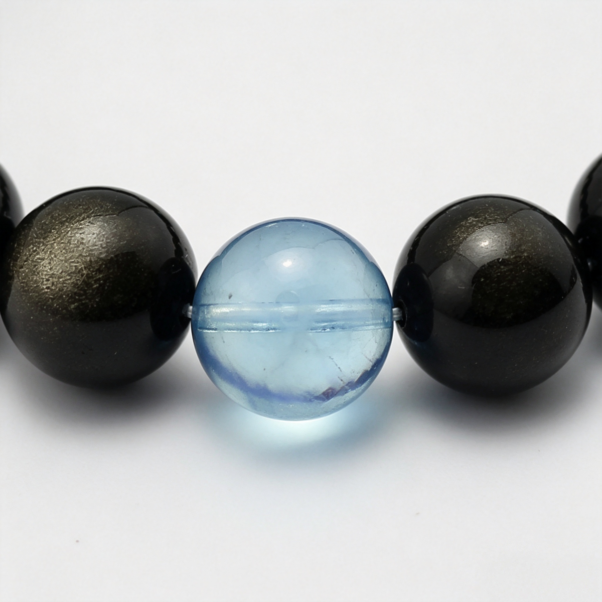 Aqua Sheen bead detail — aquamarine and gold sheen obsidian, dark with a gold glint up close.