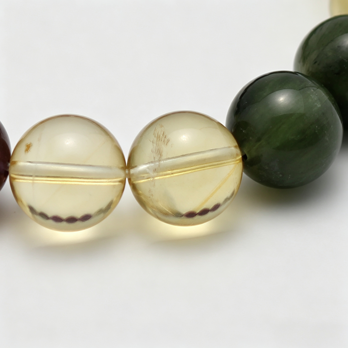 Close-up of the Verdant Flame bracelet by Krysora - bead detail, green rutilated, citrine and amethyst, natural markings