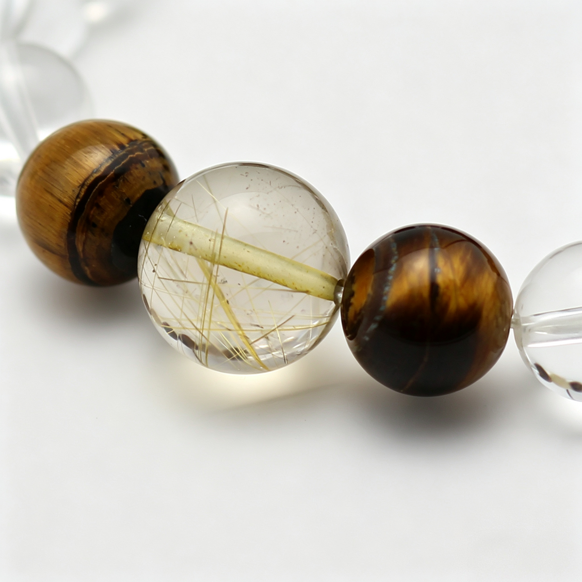 Close-up of the Gilded Silk bracelet by Krysora - bead detail, golden needles, golden-brown tiger's eye and warm clay tones, natural markings