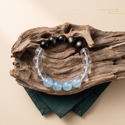 Gilded Tide bracelet by Krysora in a brand scene -- sea-blue aquamarine, clear quartz and gold sheen obsidian beads, styled in natural daylight.