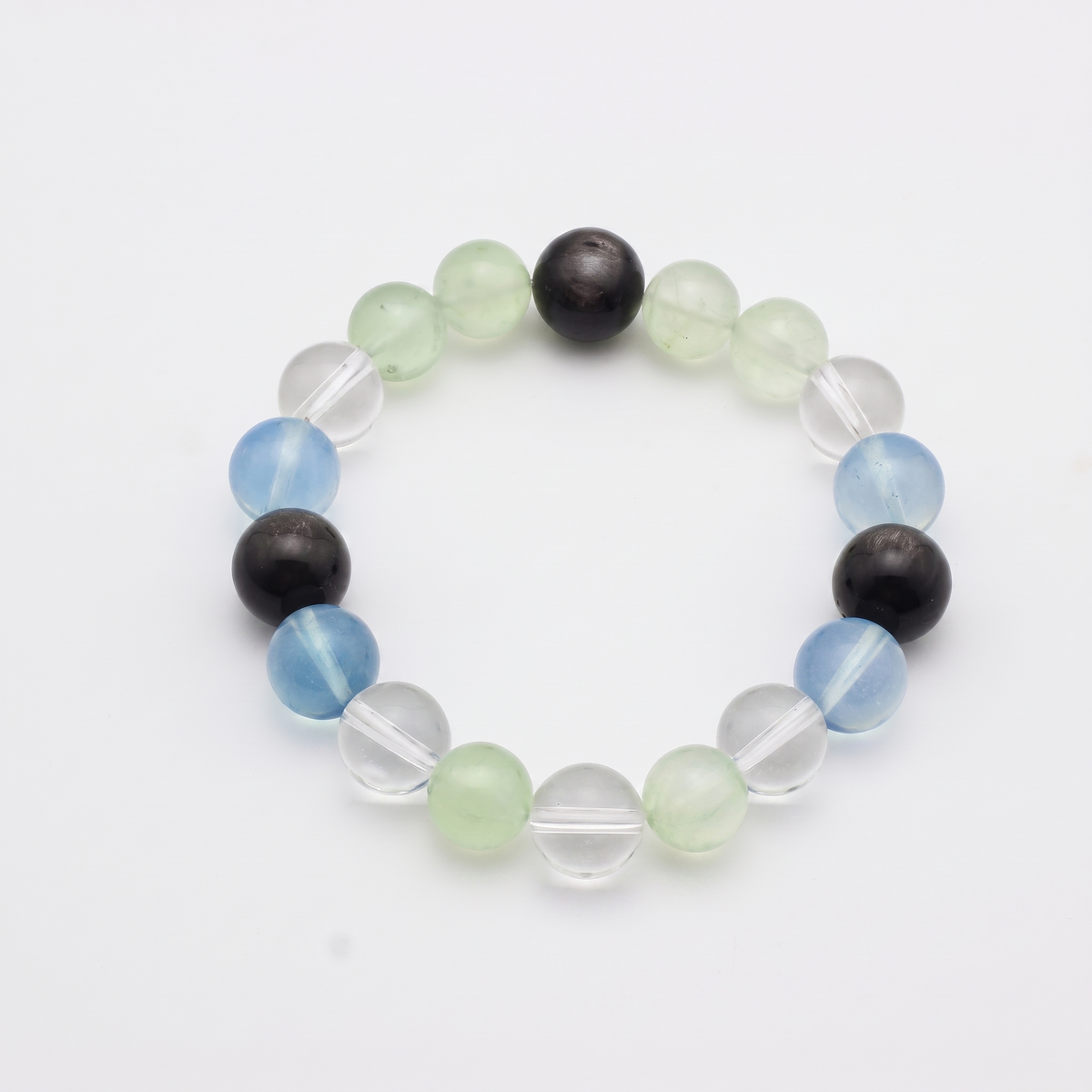Confluence bracelet by Krysora - Silver Sheen Obsidian, Aquamarine and Prehnite with Clear Quartz accents, deep blue-black and living green cool palette, product photo on white background